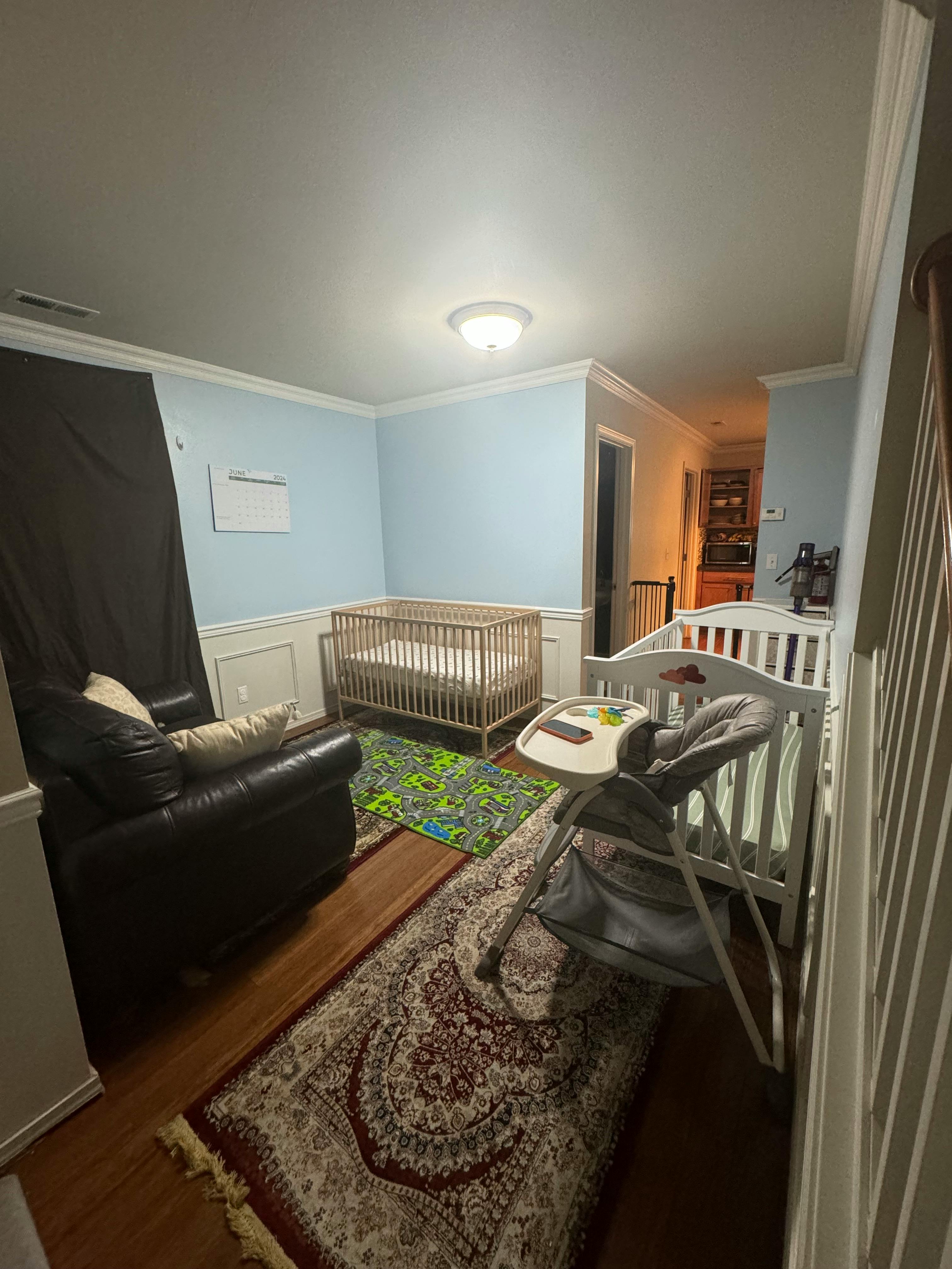 Two cribs, a high chair, and a recliner in a room