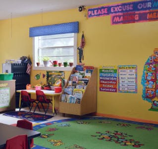 Classroom with yellow walls, small table and chairs, and book display