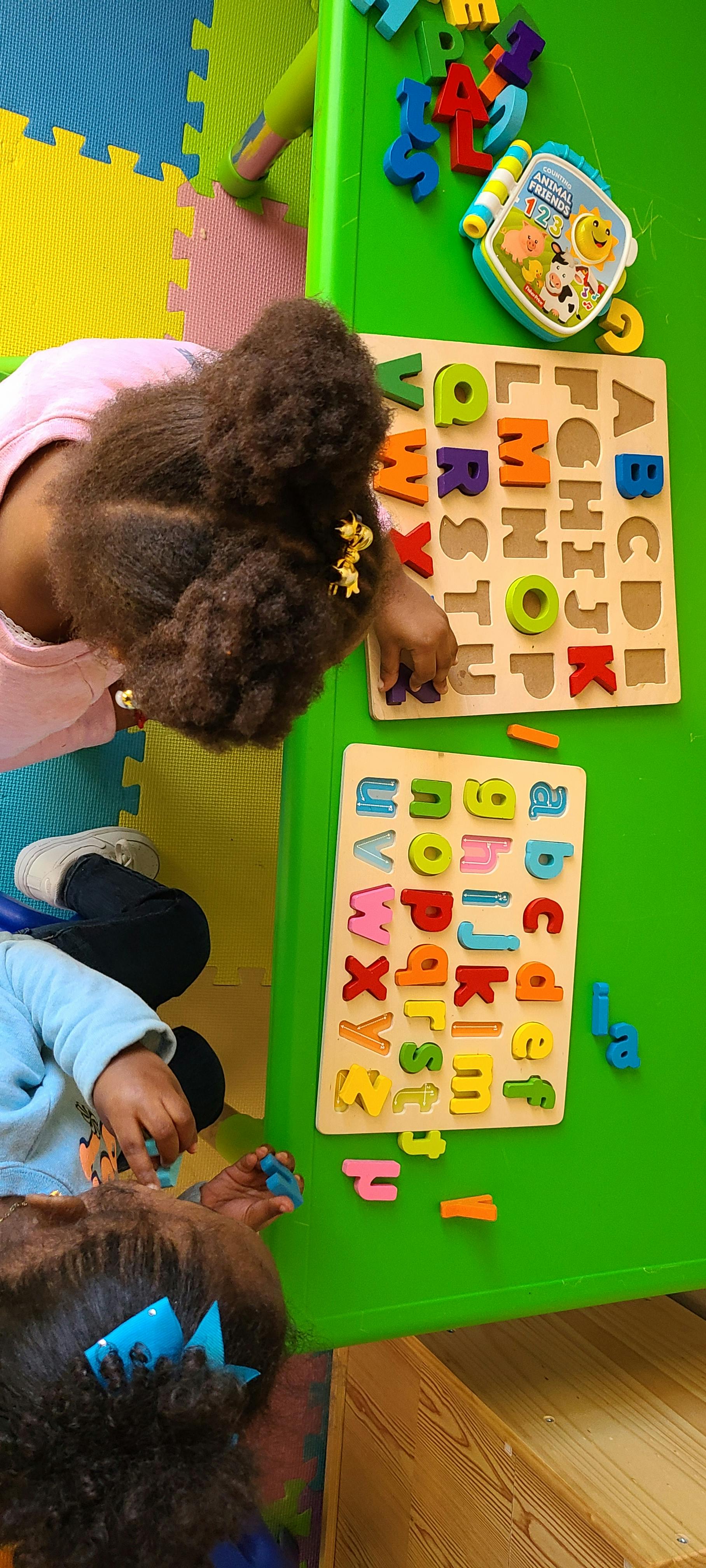 Child playing with alphabet puzzles on a green table