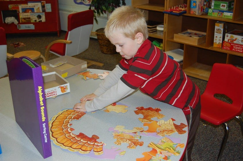Child playing with a puzzle on a table