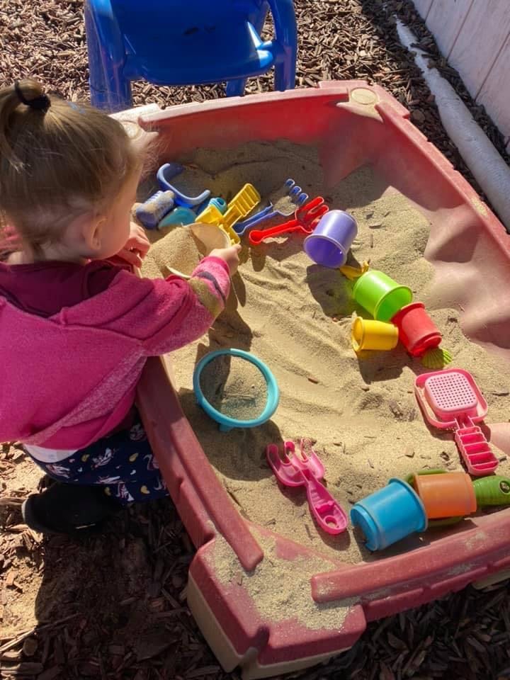Child playing in a sandbox with colorful sand toys