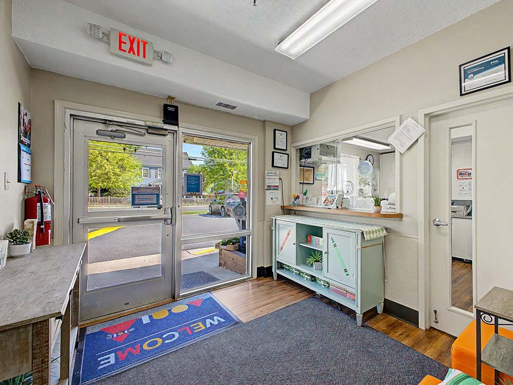 Entrance of a building with an EXIT sign above the door and a welcome mat