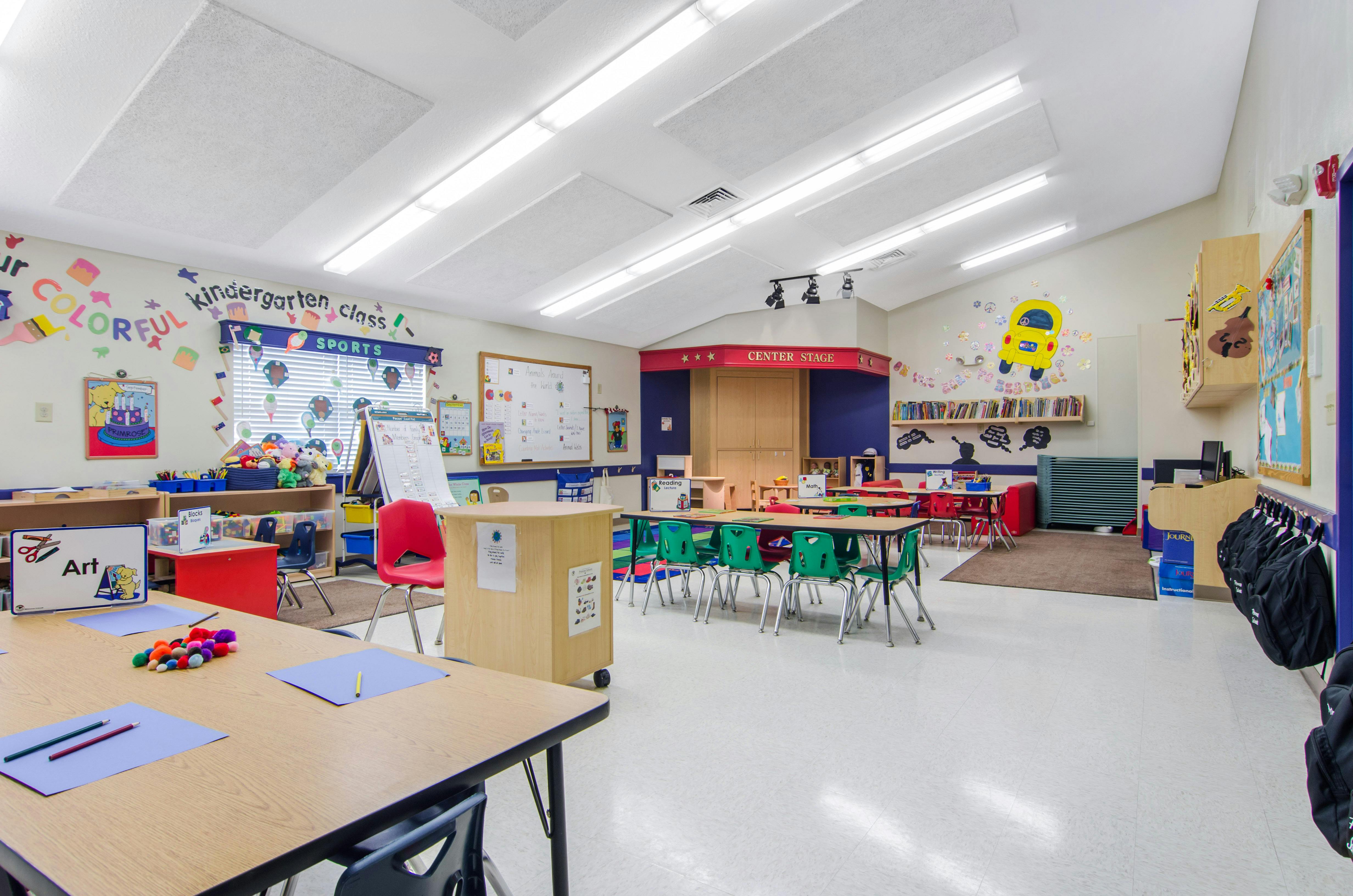 An empty kindergarten classroom with tables, chairs, and colorful decorations