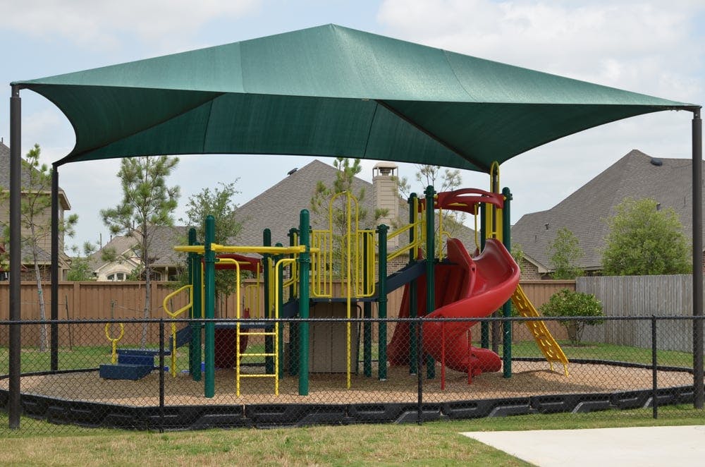 Playground with slides and swings under a large green shade structure