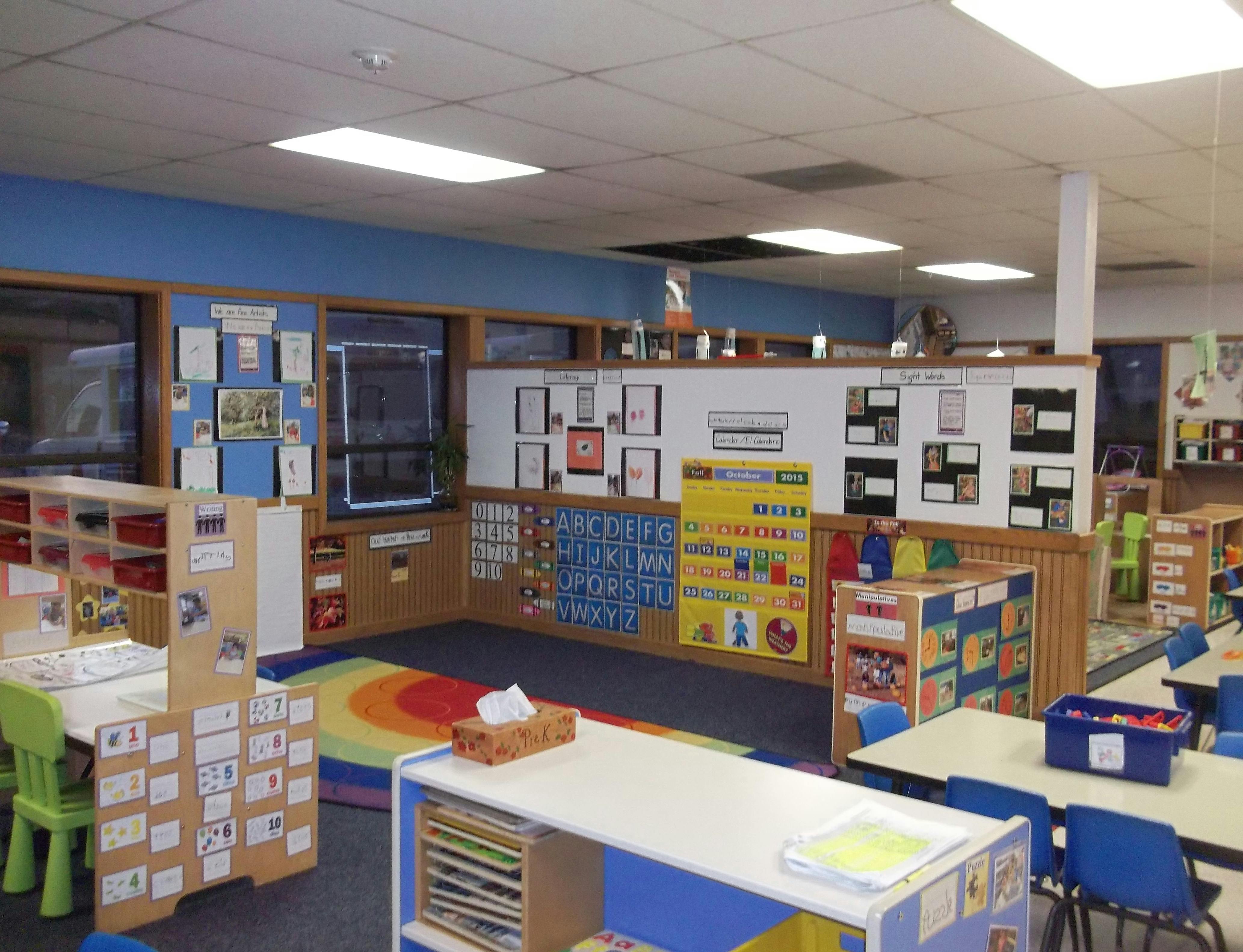 Classroom with colorful rug, tables, chairs, and alphabet and number charts