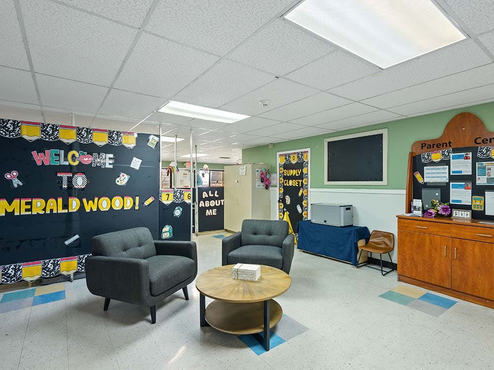 Lounge area in a school with chairs and a \"Welcome to Emerald Wood!\" sign