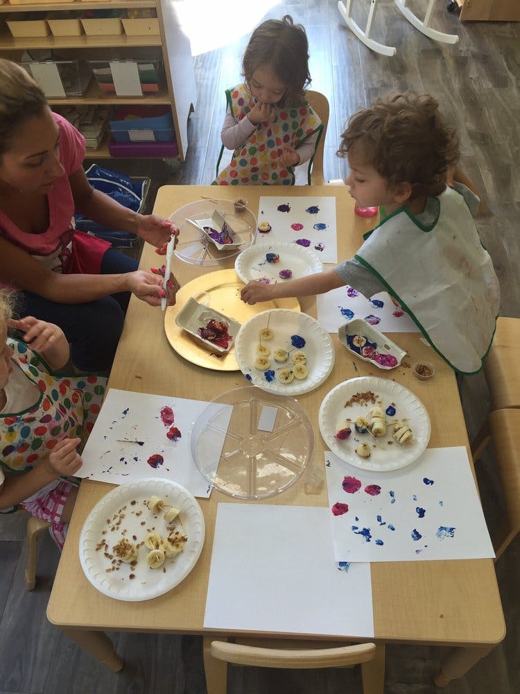 Adult and children at a table with art supplies and paper