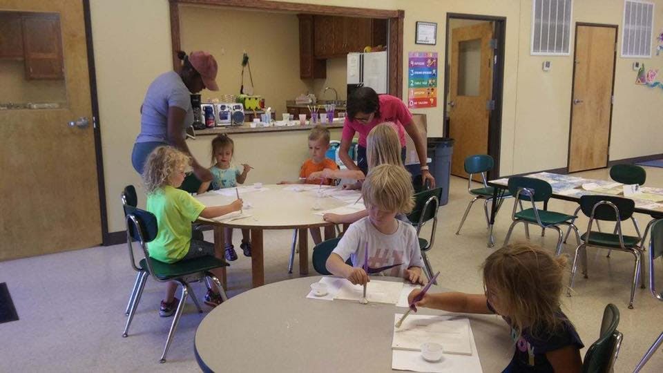 People and children at tables in a room