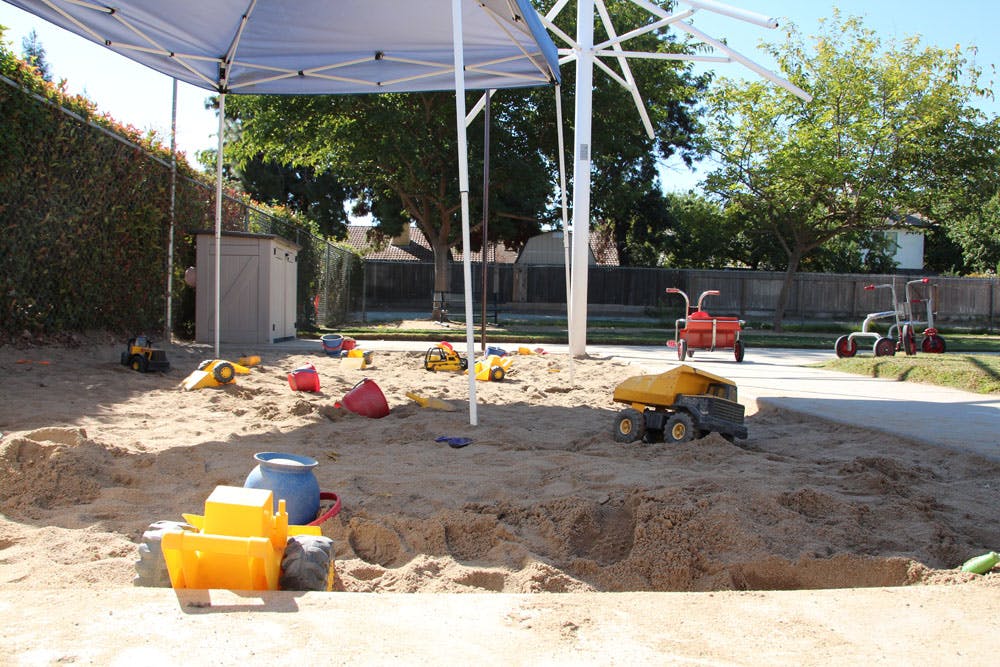 Sandbox with various toys under a canopy