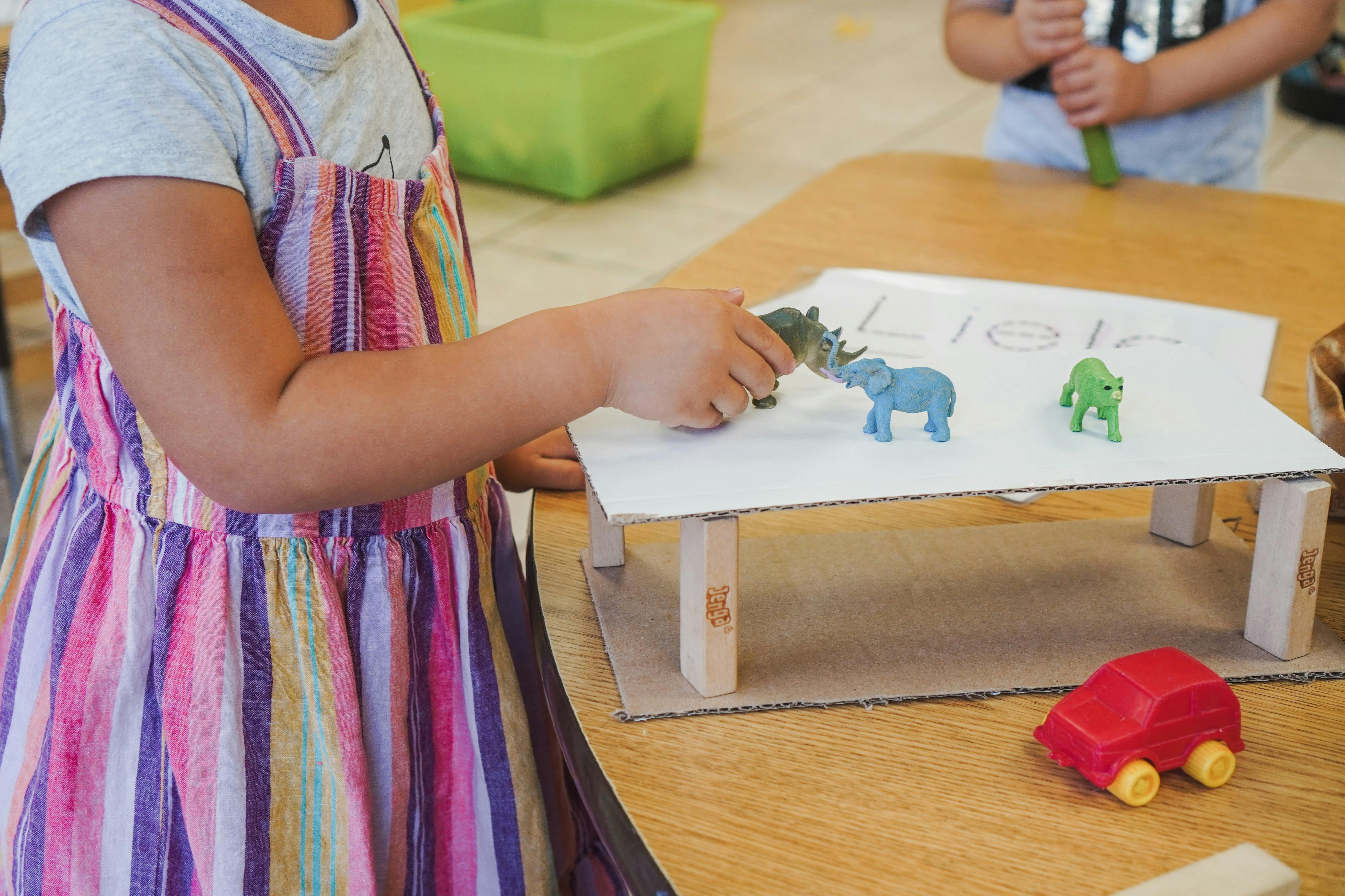 Child playing with animal figurines on a small table