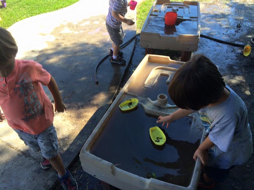 Child playing with toy boats in a water table