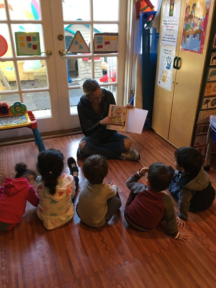 Person reading a book to children in a classroom