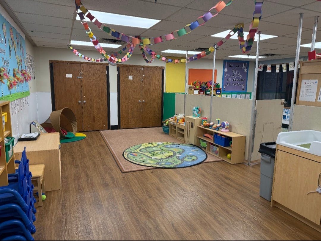 Colorful classroom with play tunnel, rugs, and shelves of toys