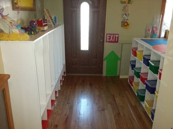 Hallway with cubbies, shelves with colorful bins, and an exit sign