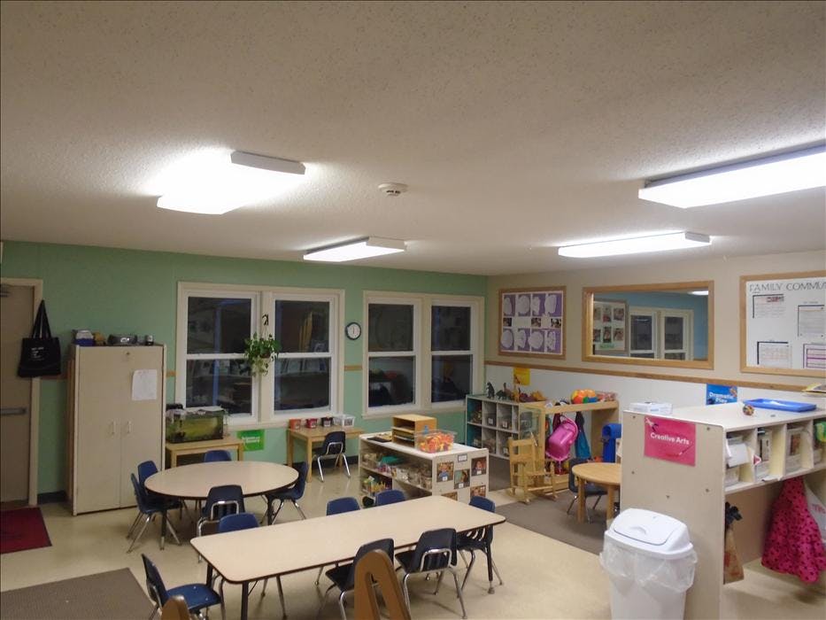 Empty classroom with multiple tables, chairs, and learning materials