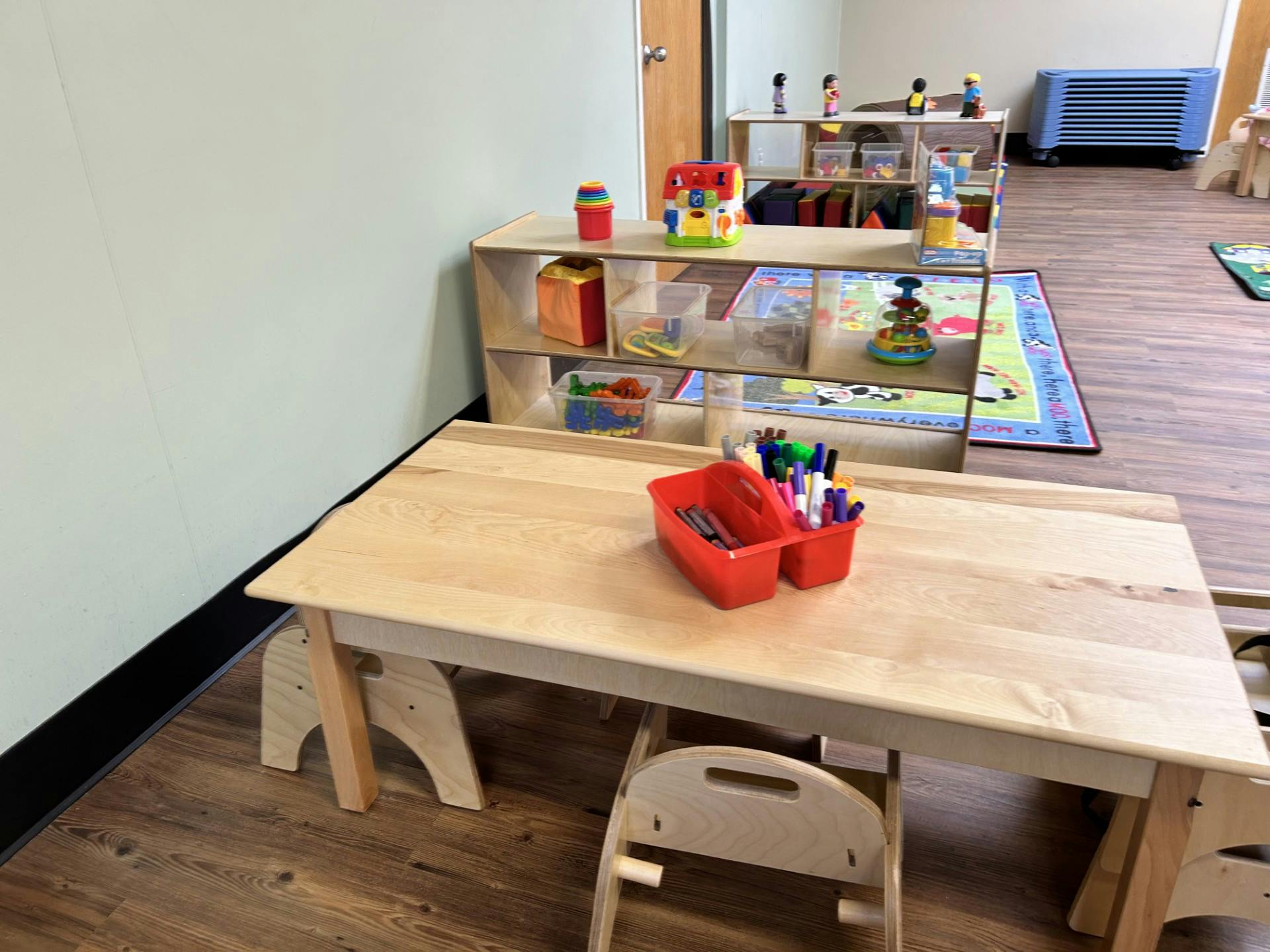 Classroom with child-sized table and chairs, shelves of toys and learning materials