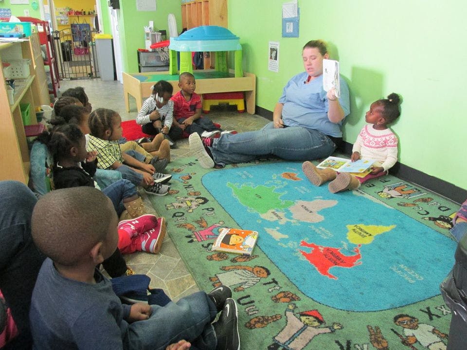 Person reading to a group of children in a classroom