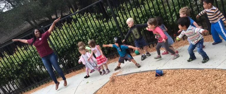 Person with arms out and children running on a path
