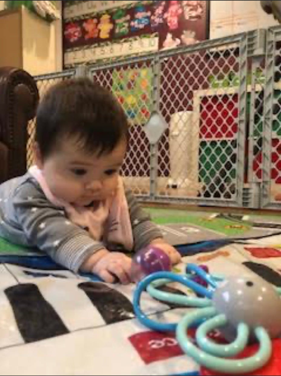 Child lying on a play mat reaching for a toy
