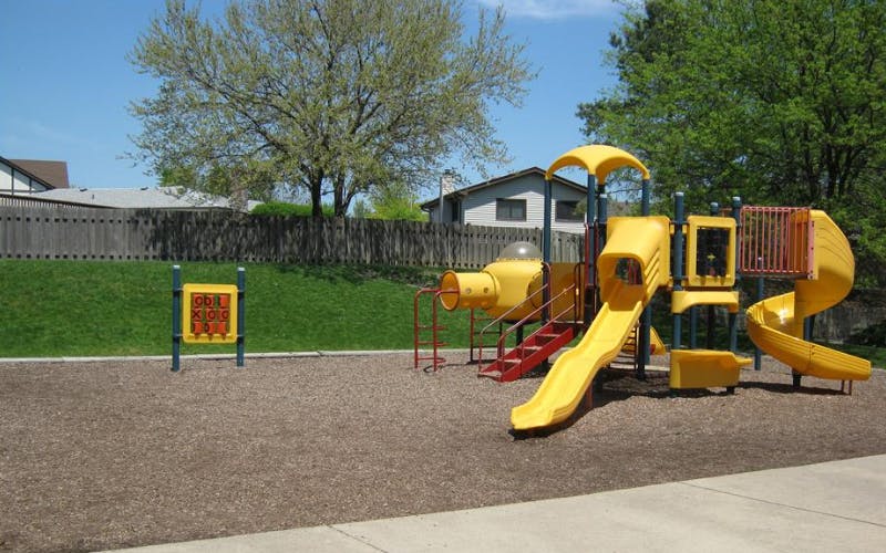 Empty playground with yellow slides and red stairs on wood chips