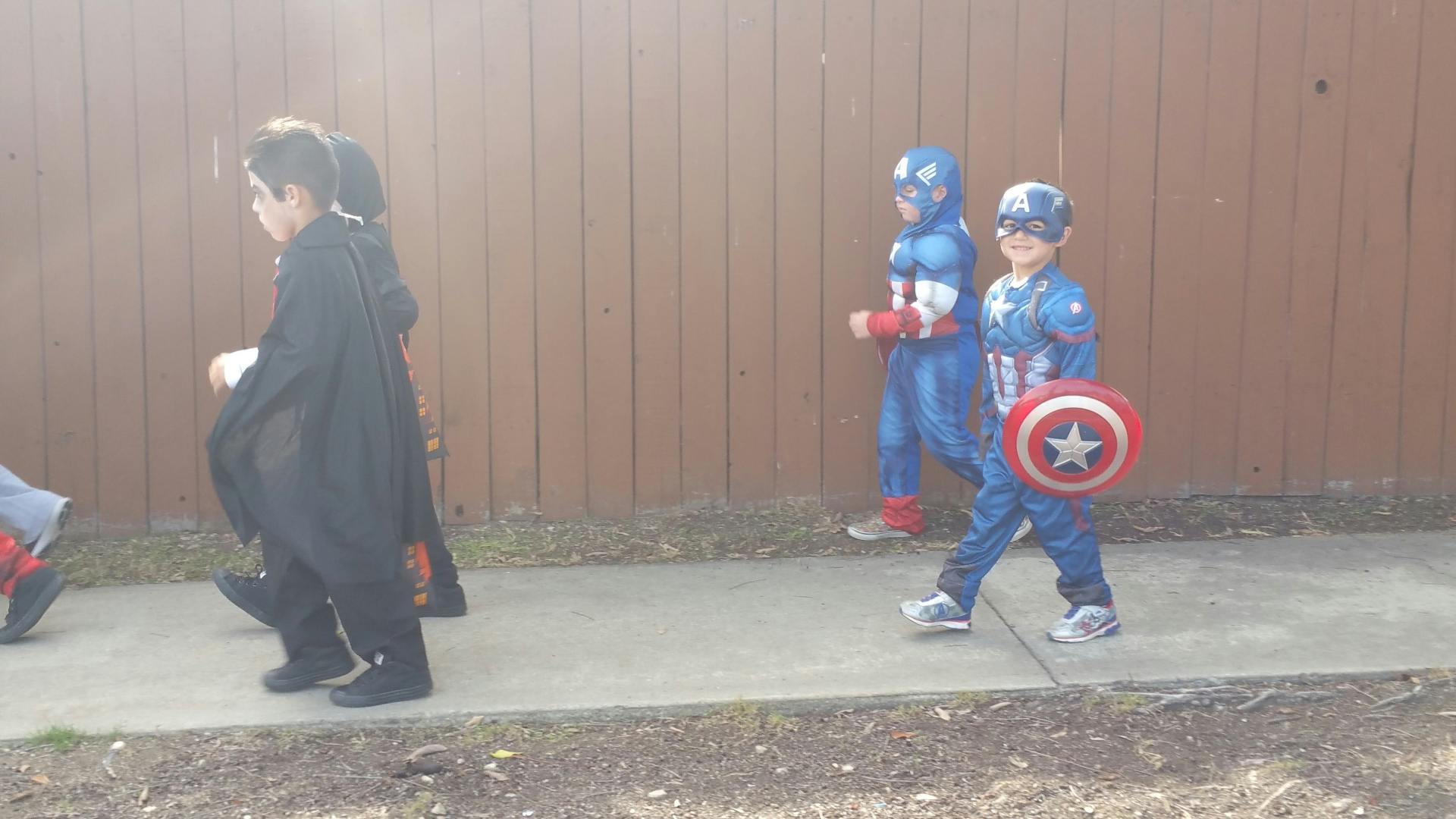 Children in costumes walking on a sidewalk