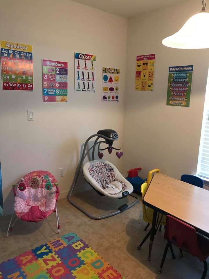 Baby swing, bouncer, and child-sized table with chairs in a room with educational posters