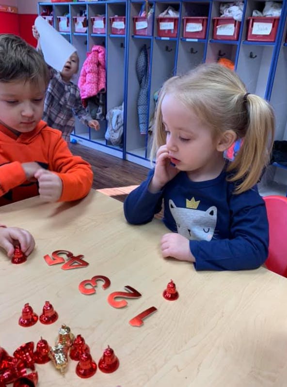 Two children at a table with red numbers and bells