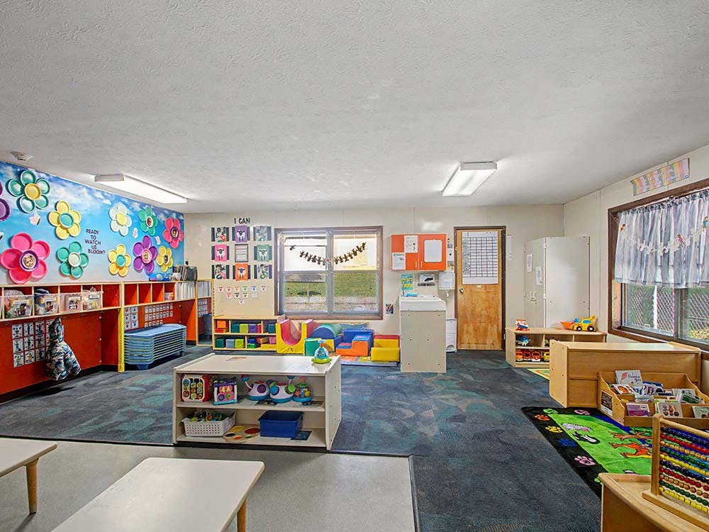 Classroom with colorful wall decorations, small tables, and learning materials