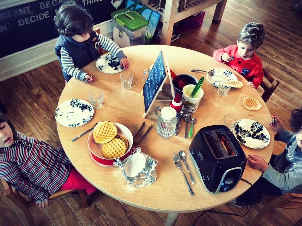 Children sitting around a table with waffles and a toaster