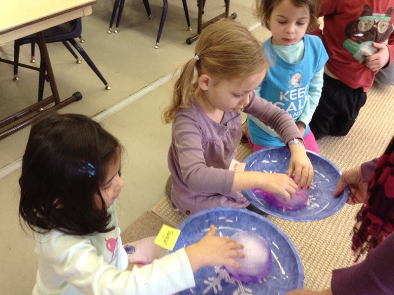 Children playing with water and ice in blue bowls