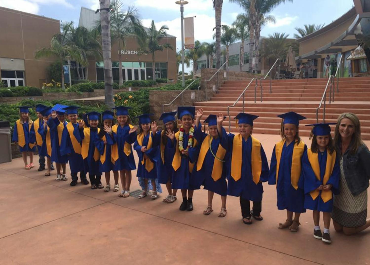 Children in graduation caps and gowns with an adult