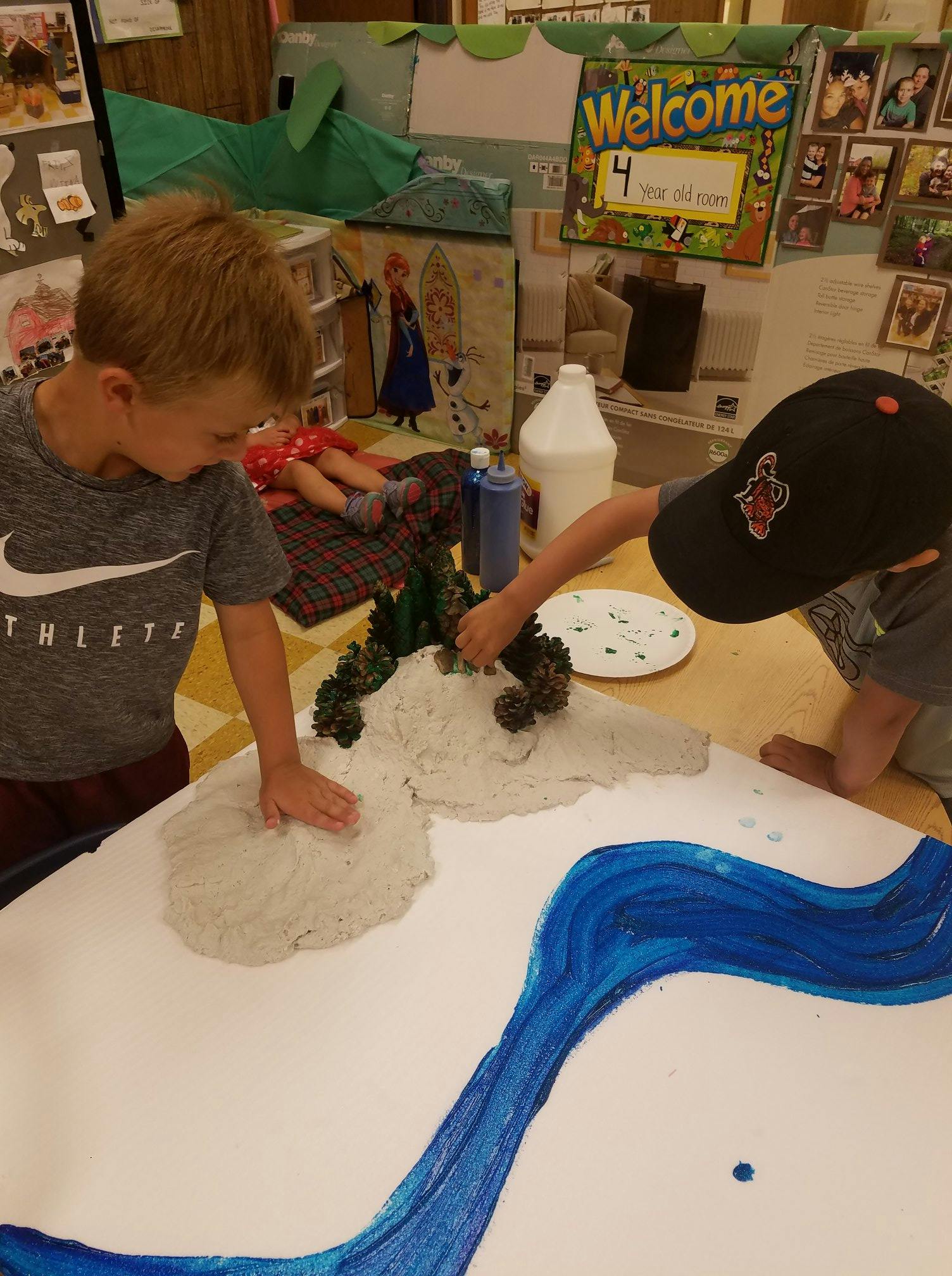 Two children creating a landscape with white and blue paint