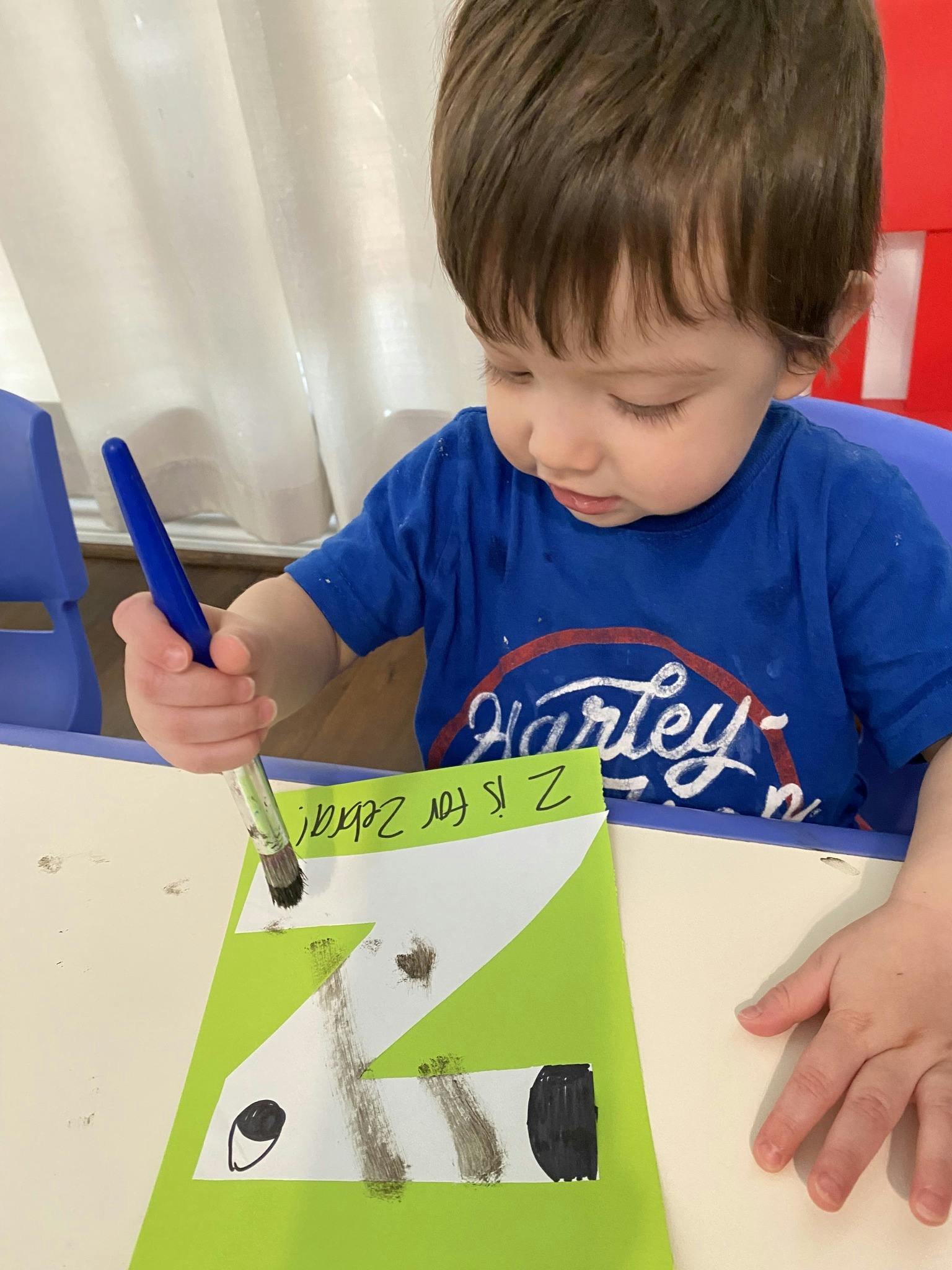 Child painting a craft with the letter Z and text "Z is for Zebra"
