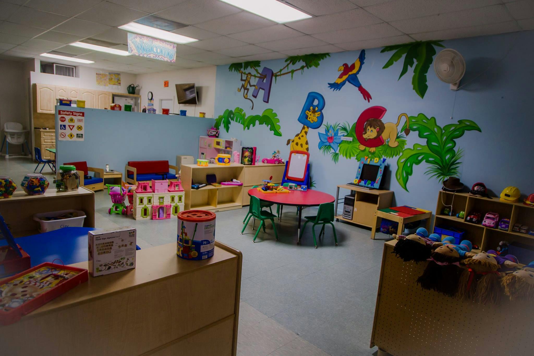Playroom with colorful wall murals, small tables, and toys