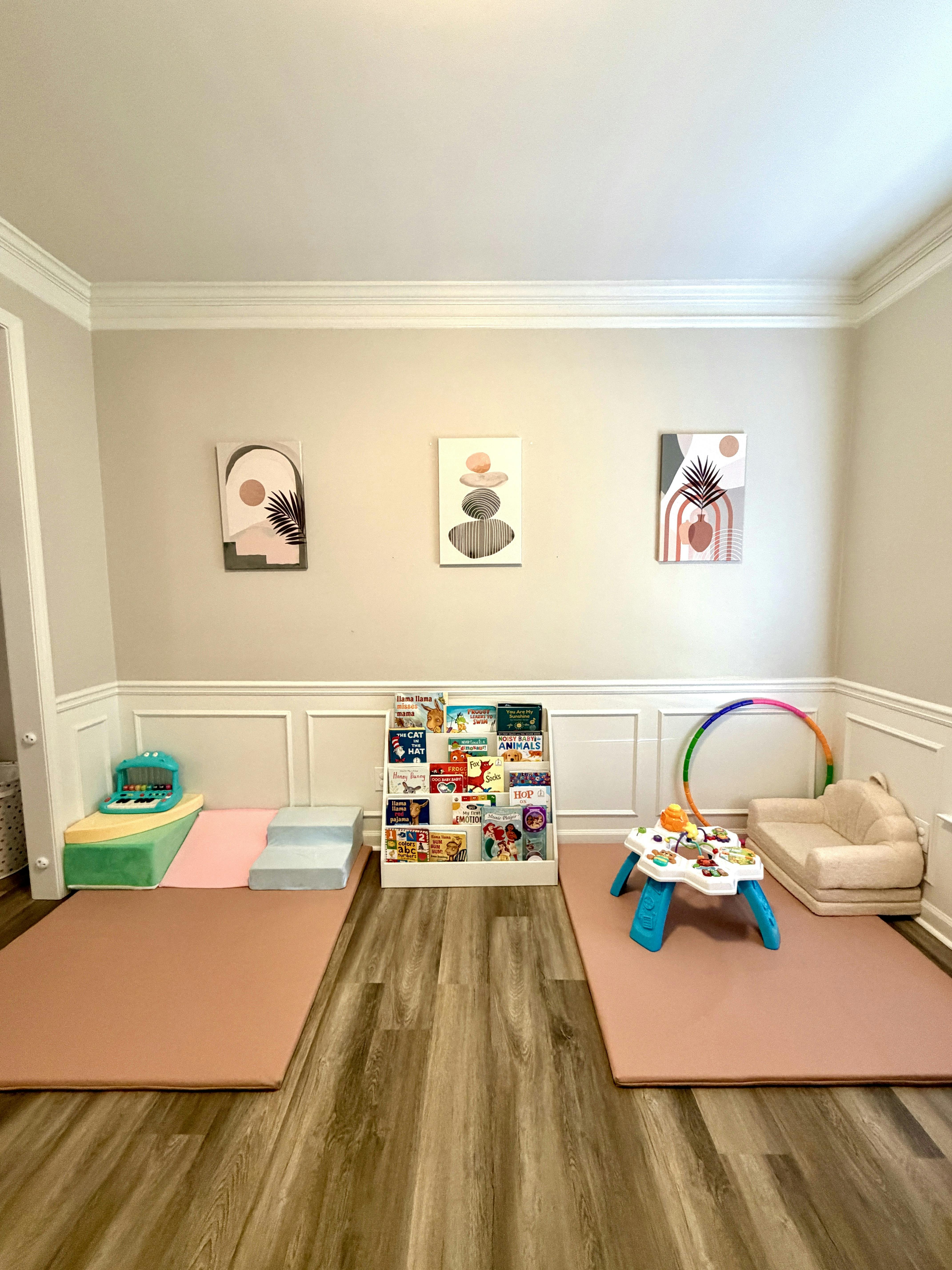 Playroom with floor mats, soft climbing blocks, book rack, and activity table