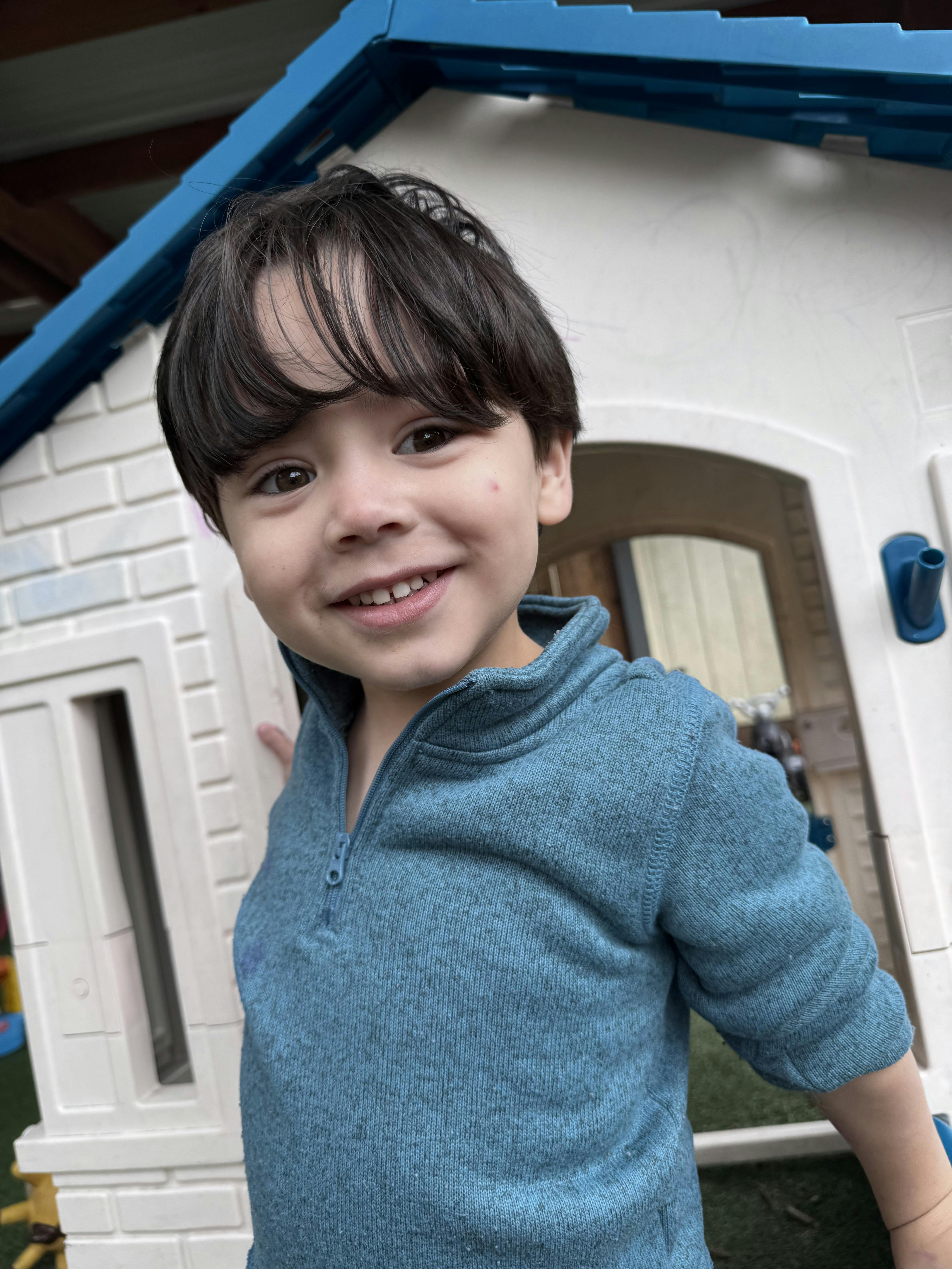Smiling child playing in a toy playhouse