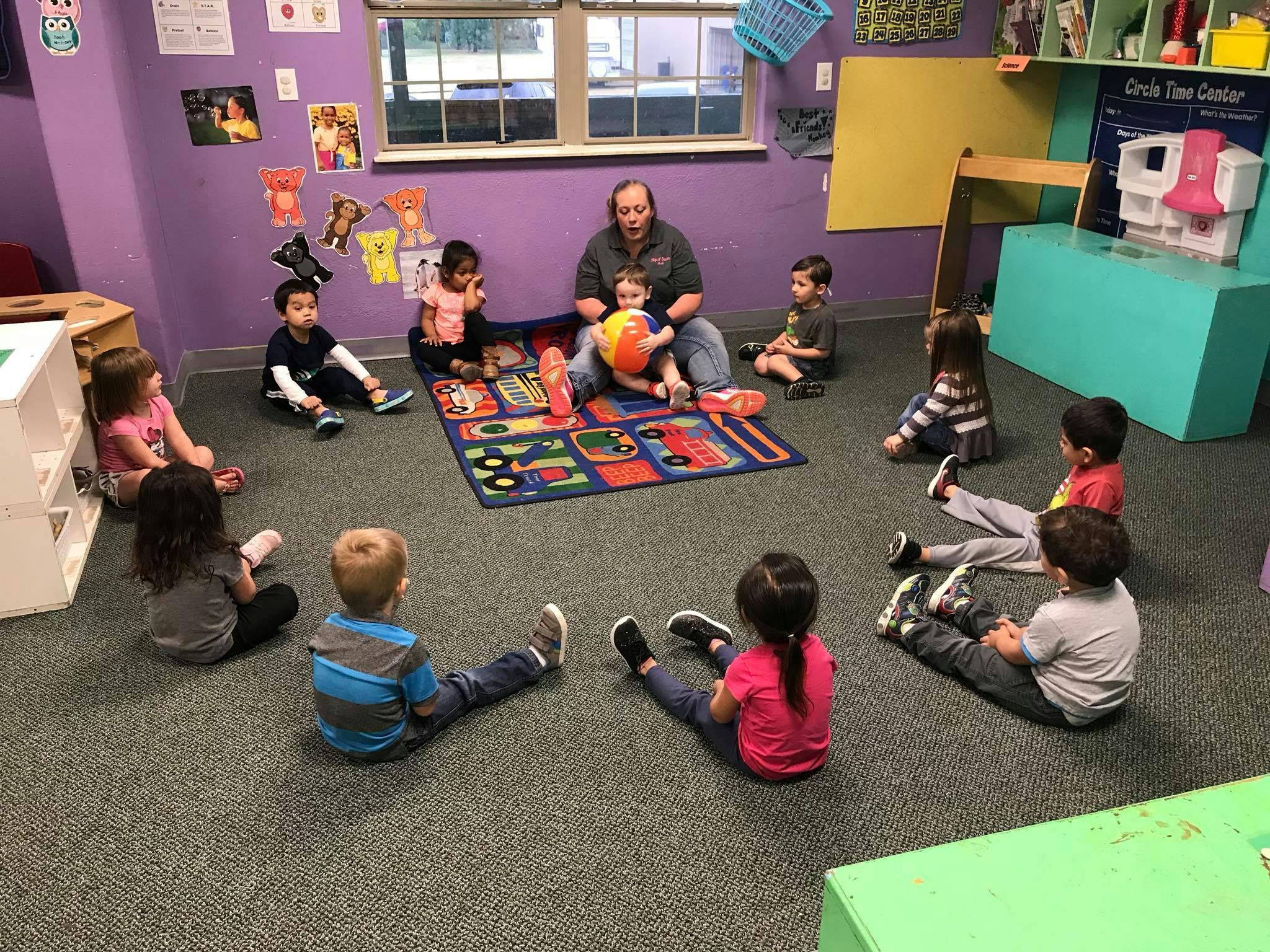 Adult and children sitting on a rug in a classroom