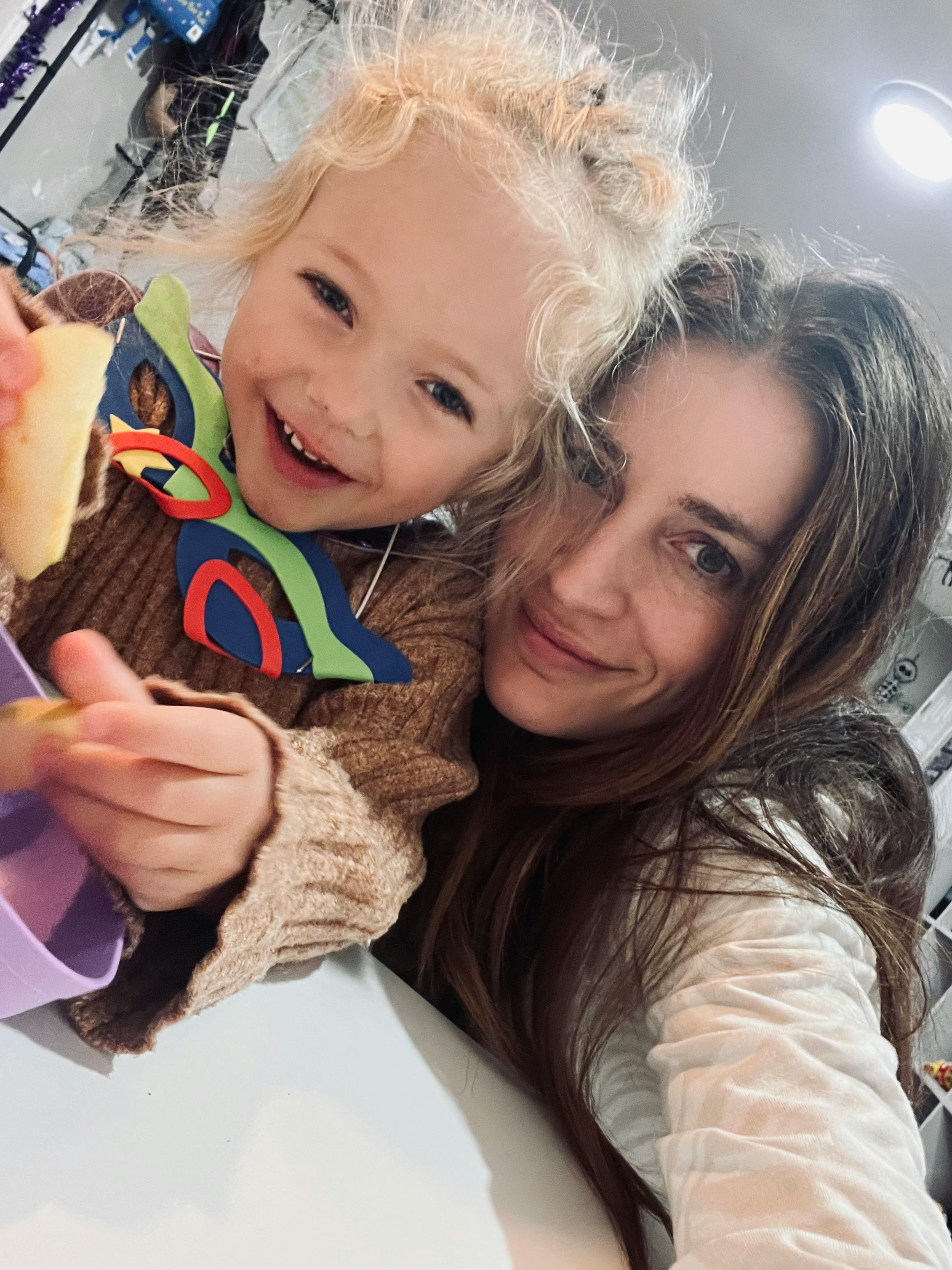 Person and child looking at camera, child holding food