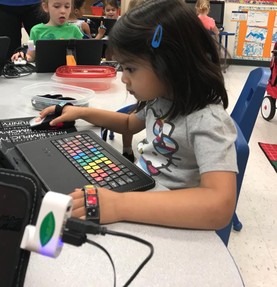 Child using a laptop with a colorful keyboard and a mouse
