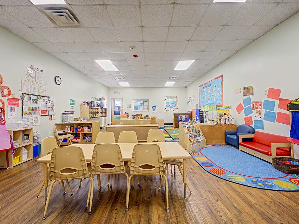 Empty classroom with tables, chairs, and colorful decorations on the walls