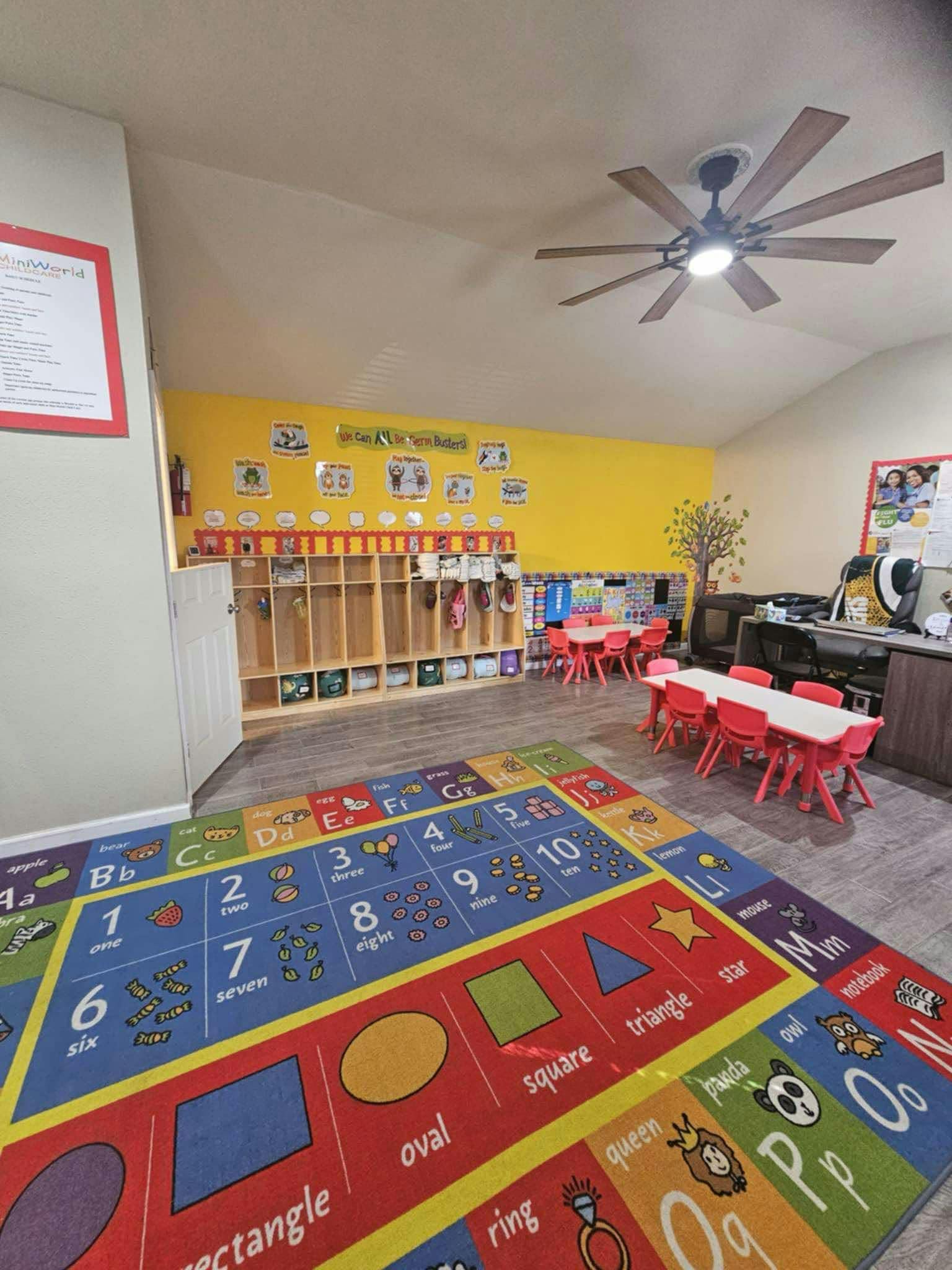 Classroom with colorful rug, cubbies, and small tables with red chairs