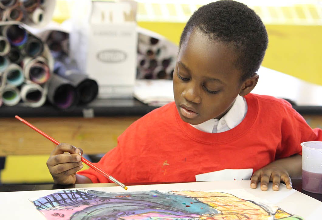 Child painting on paper with a paintbrush
