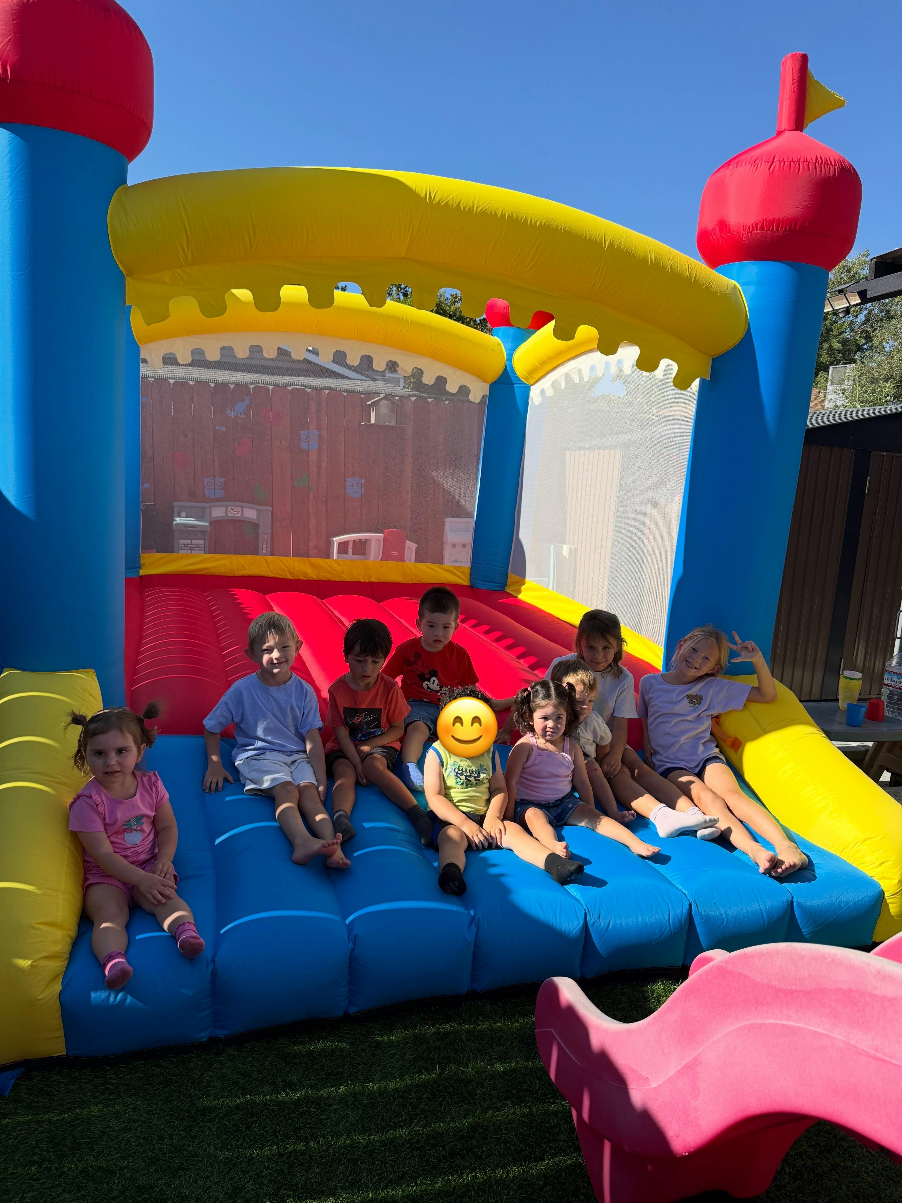 Group of children sitting inside a colorful bouncy castle