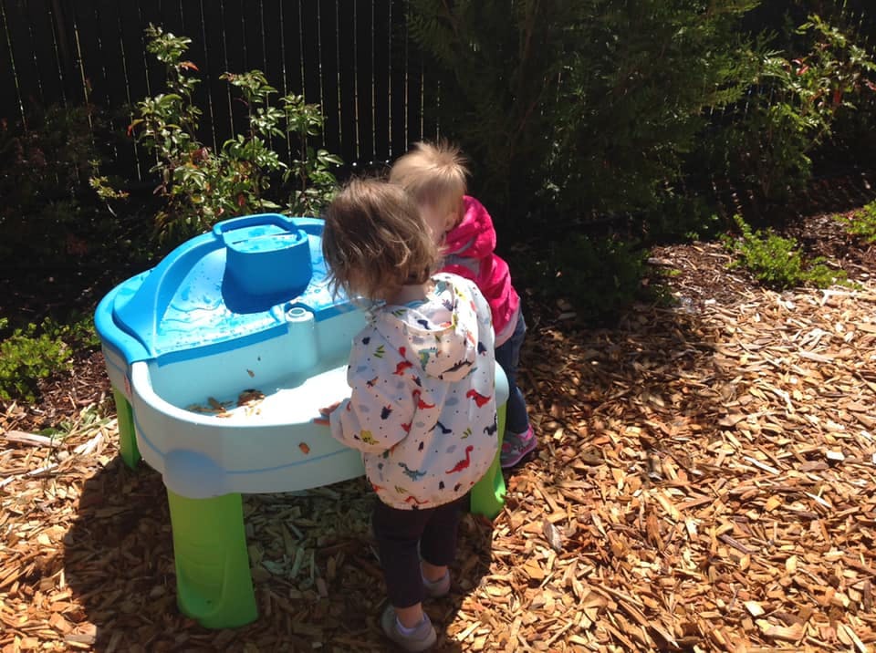 Two children playing at a water table outdoors