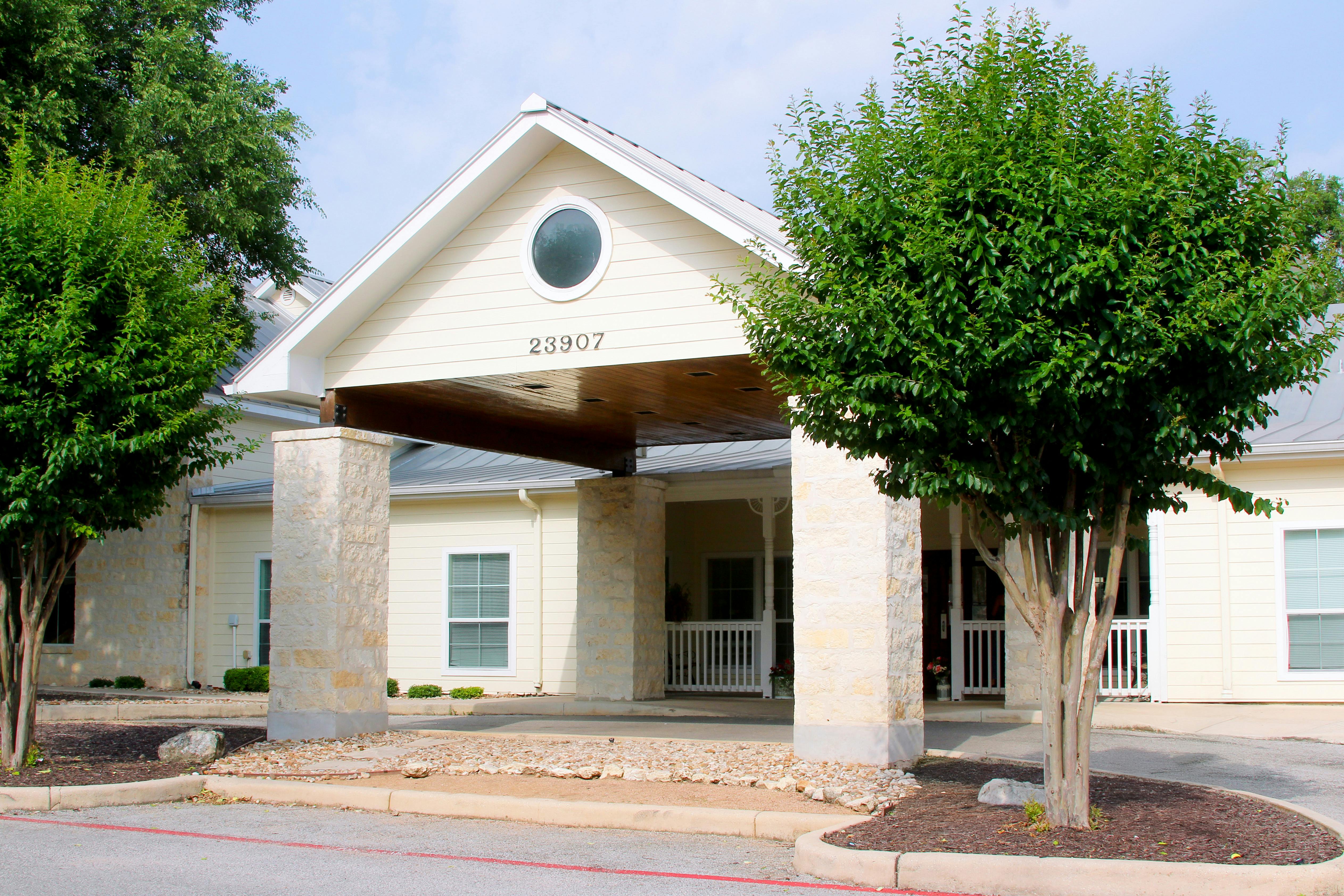 Front entrance of a building with a covered driveway and trees