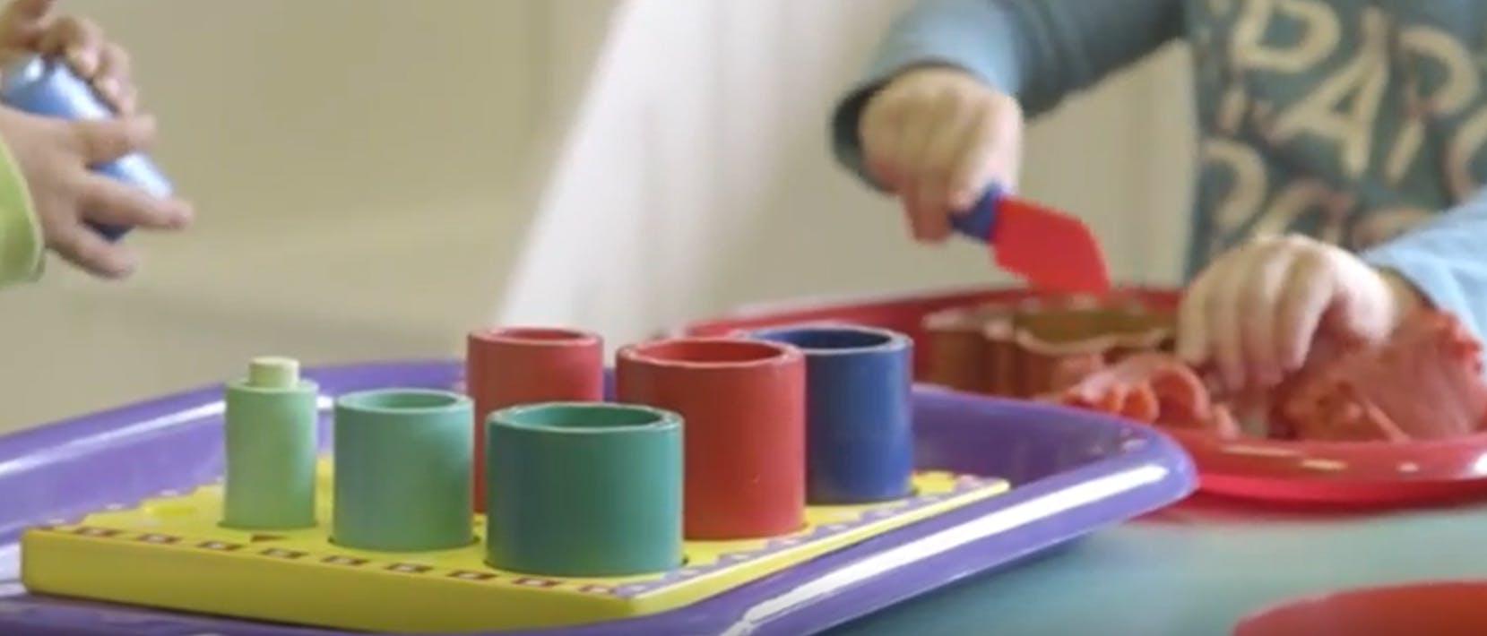Child playing with colorful stacking toys and sand