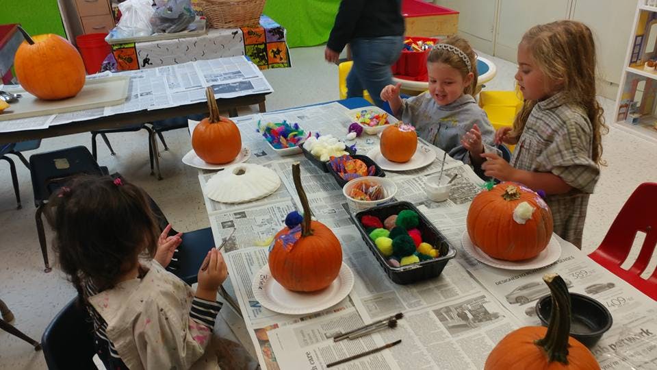 Children decorating pumpkins at a table