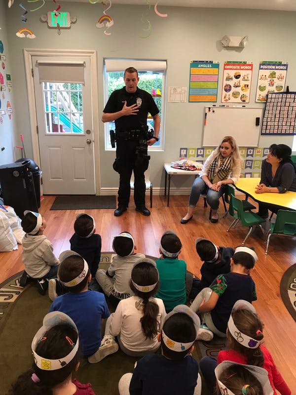 Police officer speaking to children and two adults in a classroom