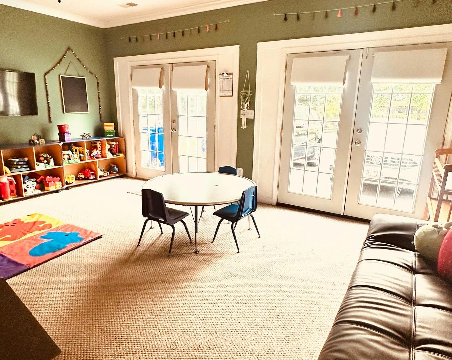 Playroom with small table and chairs, toy shelves, and colorful rug