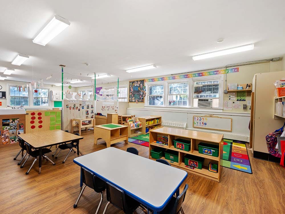 Classroom with child-sized tables and chairs, cubbies, and windows
